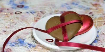 heart chocolate wrapped in red ribbon on a plate on a festive tablecloth