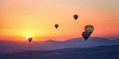 hot air balloons over mountains at sunset